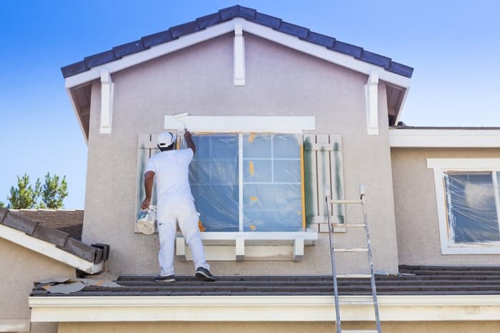 House painter applying exterior paint to a home's window trim