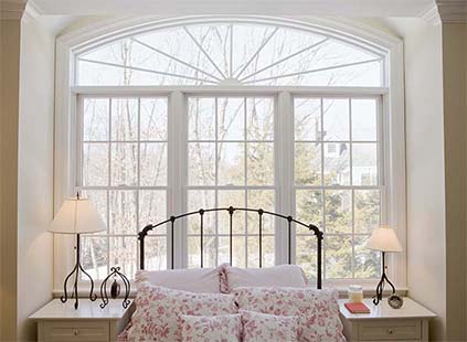 Beautiful wooden windows surround child's bed frame and night stands