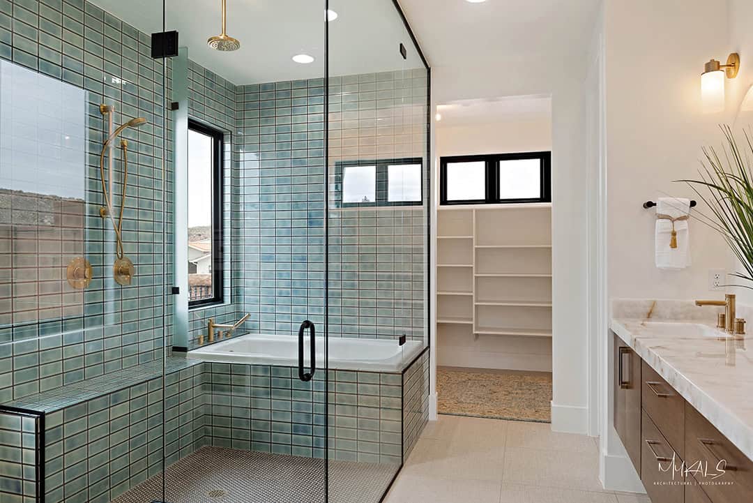 Beautiful, luxurious glass shower at a home in the Utah Parade of Homes with a bathtub in the enclosure and unique turquoise tile