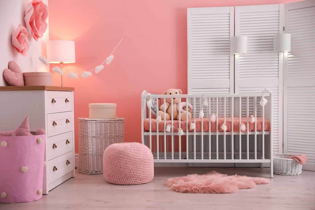 Girl's baby room interior with pink painted walls and dainty decorations such as tissue pompoms